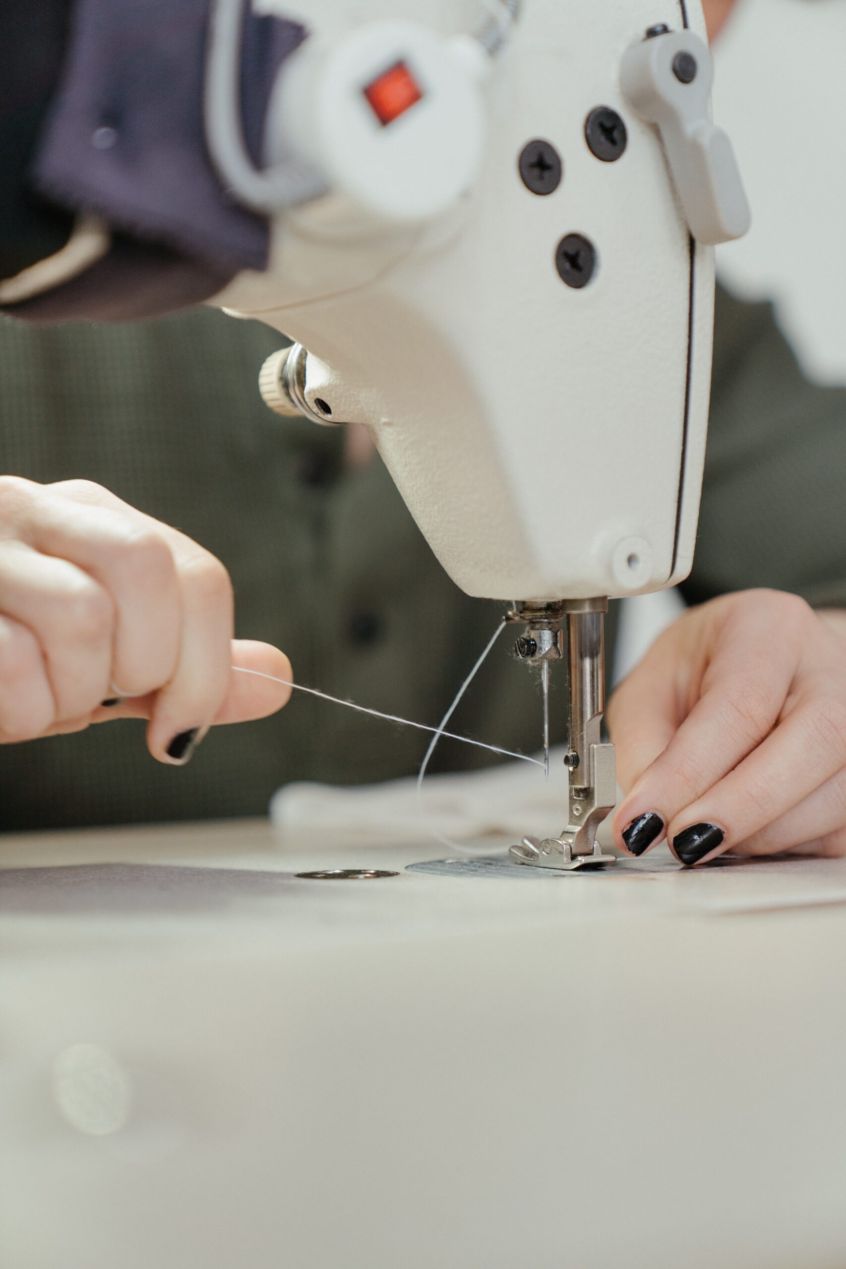 Tailor guiding thread through a sewing machine